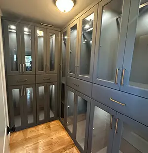 Narrow walk-in closet with elegant blue custom cabinetry