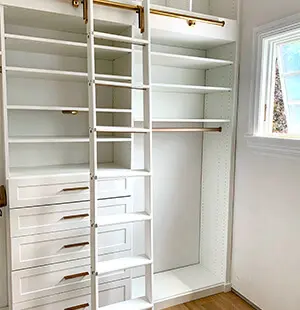 White custom closet system featuring built-in drawers, open shelving
