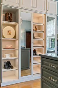 Pull-out shoe shelves with LED lighting, mirrored cabinet door, and open display shelving. Overhead cabinet storage maximizes vertical space.
