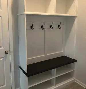White mudroom built-in with cubby storage, a dark wood bench