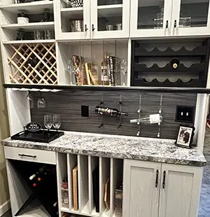 Custom home bar with wine racks, glass storage, marble countertop, under-cabinet lighting, and vertical slots for bottles and trays