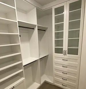 Closet cabinetry with double hanging rods and glass front doors, white shaker cabinets