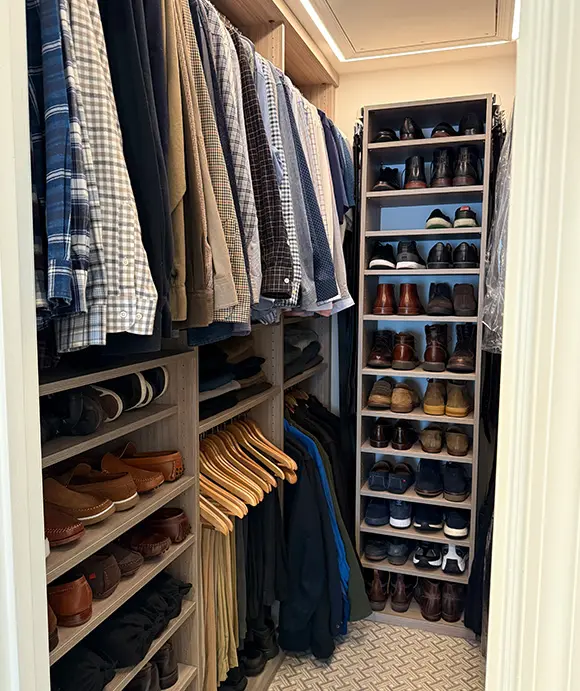 Men's walk-in closet featuring built-in shelving and hanging space, neatly organized