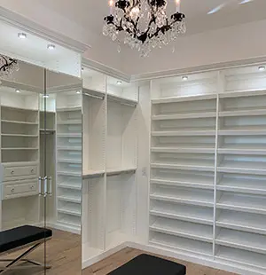 Custom walk in closet with white shelving, glass doors, and LED lighting