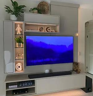 Contemporary built-in media center with floating cabinetry, integrated lighting, and display shelving surrounding a wall-mounted TV