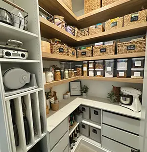Custom pantry with labeled woven baskets, clear food containers, and integrated shelving for small appliances and kitchen essentials