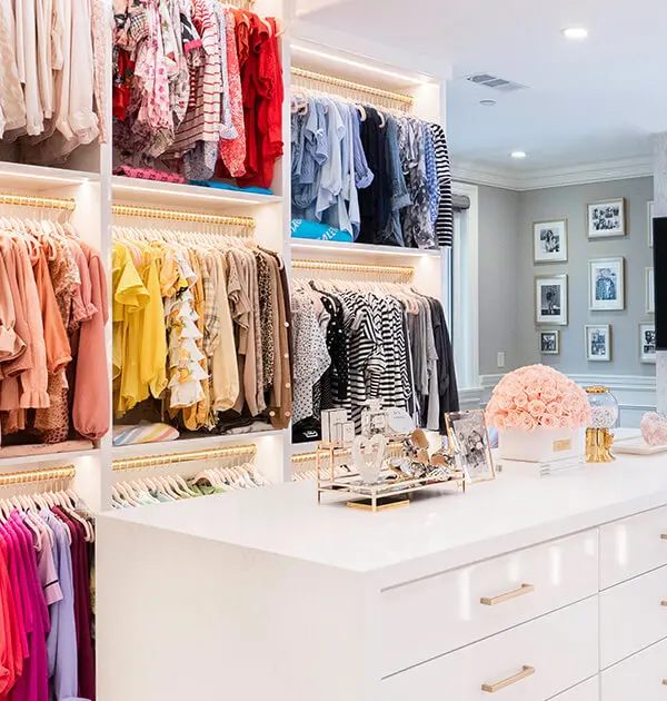 Dressing room with marble countertop island and boutique-style LED lighting strips over hanging rods
