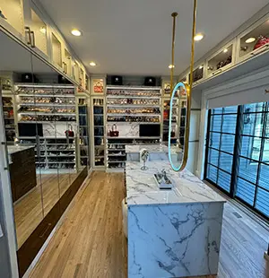 Elegant walk-in closet with floor-to-ceiling storage, mirrored cabinetry, and a central marble island