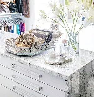 closet up of closet island with marbled top that wraps the sides and plex glass handles