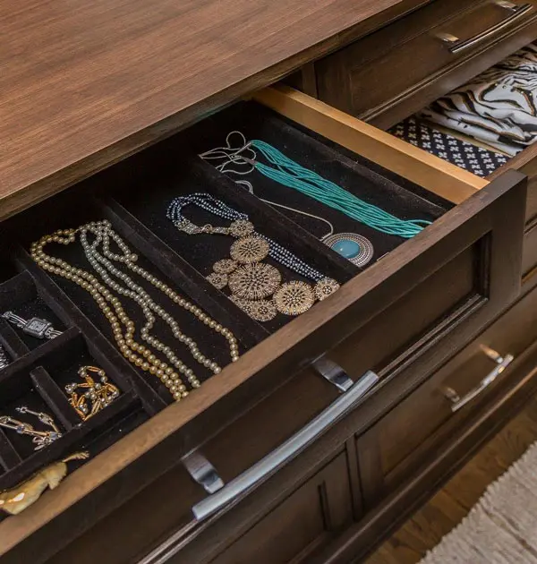 Drawer with velvet-lined compartments holding jewelry and accessories.