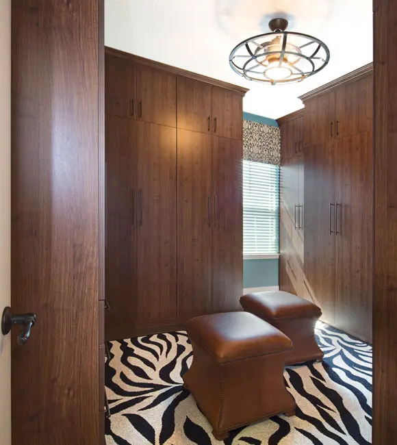 Compact wardrobe room with tall wood cabinets and two upholstered stools.