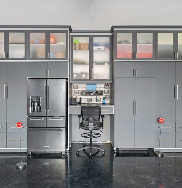 Garage storage wall with gray cabinets, a built-in workstation, and appliance storage.