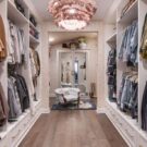 An elegant, custom-painted white walk-in closet accented with specialty drawer faces, architectural crown molding, and custom baseboards for a seamless built-in look.