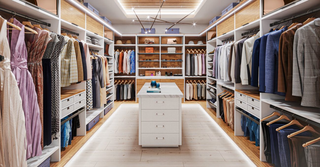 Elegant luxury closet with floor-to-ceiling storage, LED underlighting, valet rods, glass shelving, and a sleek center island with Raised Panel drawers.