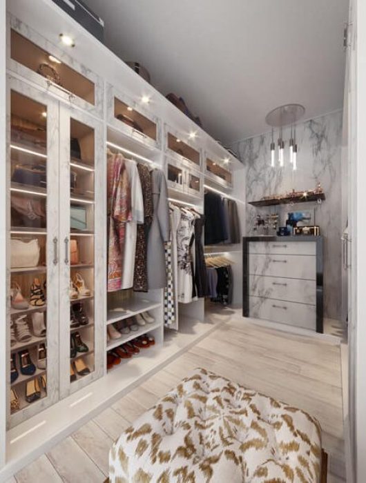 Boutique-style closet with marble-finished Raised Panel doors, LED-lit shelves, and glass drawer fronts.