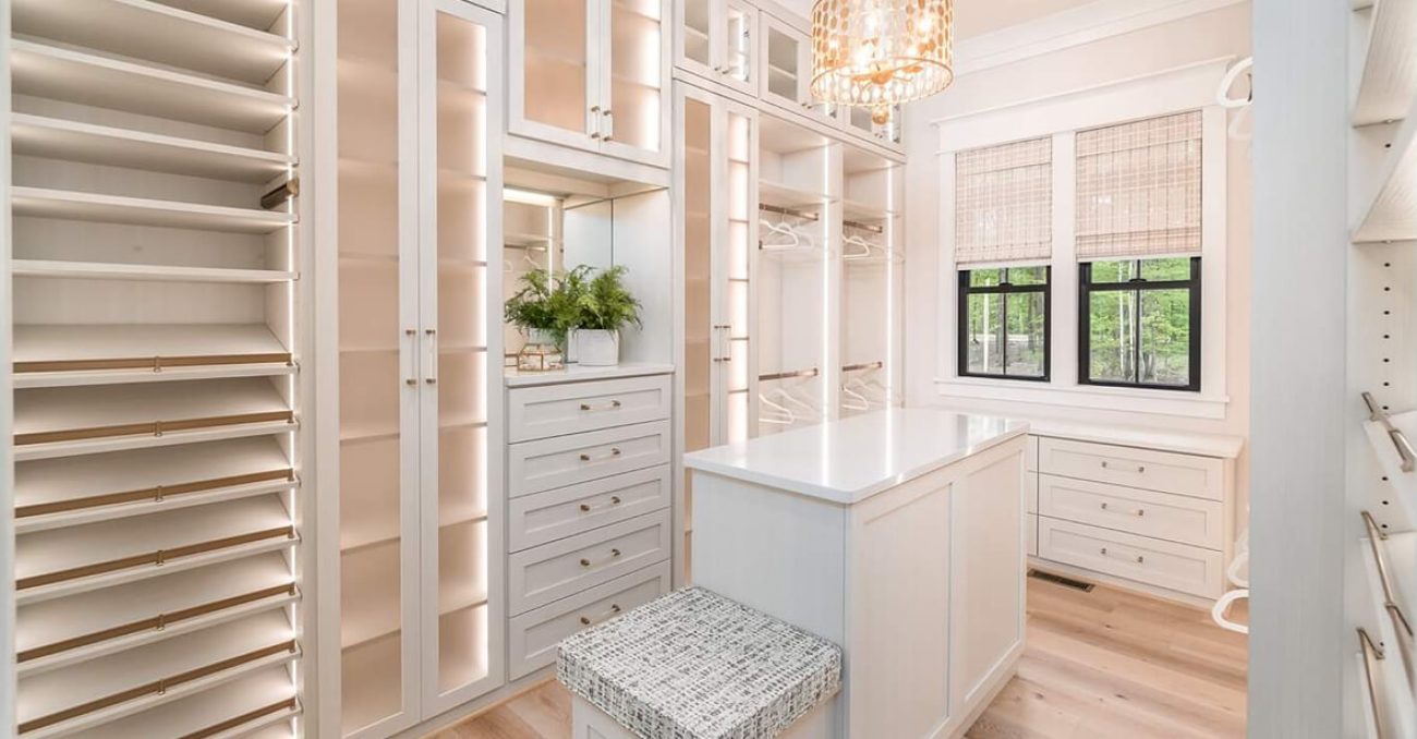 Luxury closet withLED-lit shelving, Raised Panel drawers, a mirrored vanity, and adjustable shoe fences.