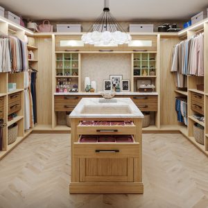 Glass-top island, velvet-lined jewelry drawers, and LED wardrobe lighting. Custom cabinetry in Rhapsody Melamine with concealed pull-out hampers, open cubbies, and dedicated vanity shelving.