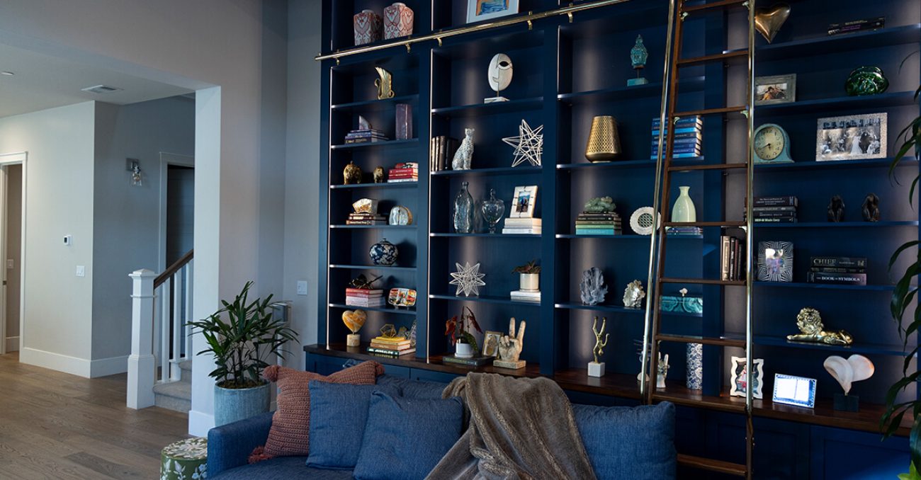 Library book case with strip lighting and rolling ladder in navy blue
