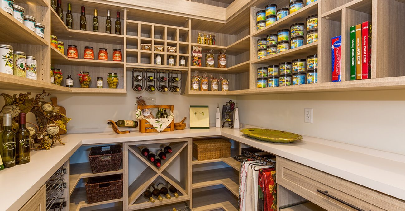 Custom walk-in pantry with light wood tones with wine racks, spice shelves, and built-in storage for preserves and oils.