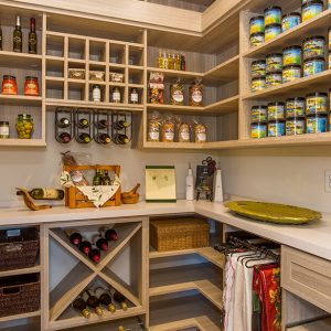 Custom walk-in pantry with light wood tones with wine racks, spice shelves, and built-in storage for preserves and oils.