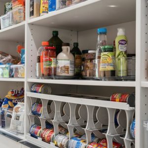 Custom pantry with labeled clear bins, rotating trays, and a can dispenser for organized food and drink storage.