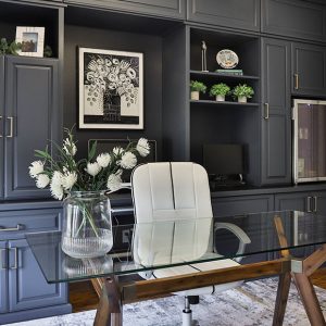 Custom home office system with upper and lower cabinetry, glass display doors, and crown molding.