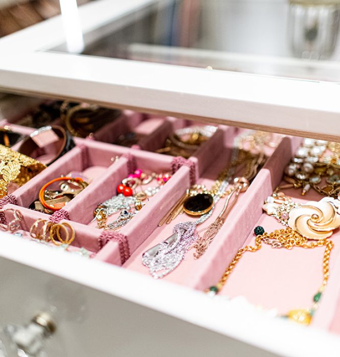 Jewelry drawer with velvet-lined compartments and a glass top integrated into a custom island unit.