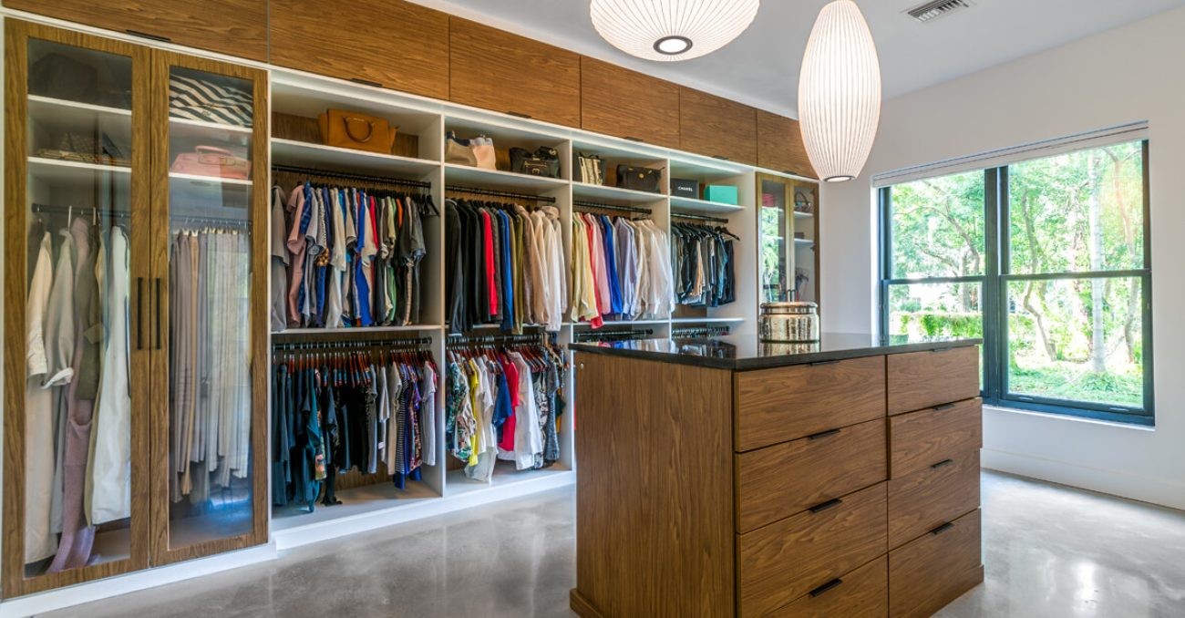 Walk-in closet with floor-to-ceiling wood paneling, black glass cabinetry, and LED-lit shelving