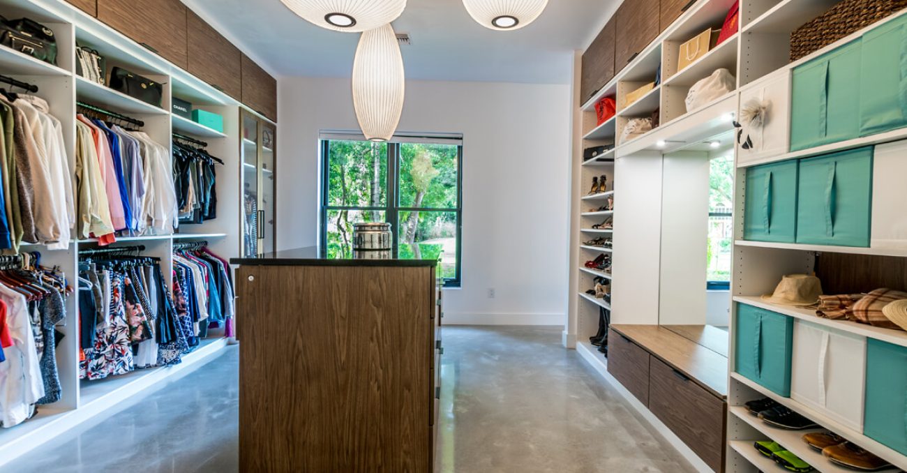 Custom closet with white and walnut tones, featuring teal pull-out fabric bins, a full-length mirror, and dedicated shoe cubbies.