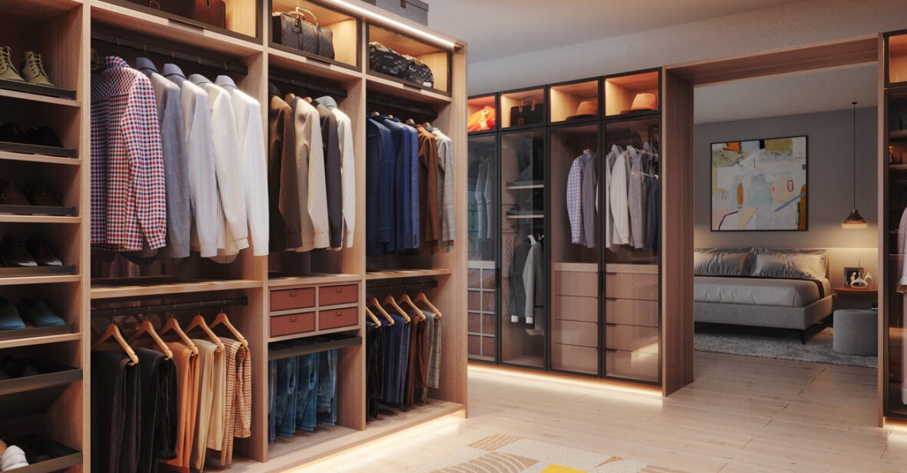 Contemporary walk-in closet in warm woodgrain finish with glass-front cabinetry, integrated lighting, and dual hanging sections. Open cubbies and pull-out storage boxes provide sleek organization.