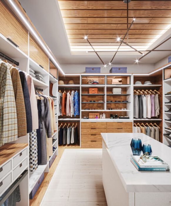 Contemporary closet with sleek wooden paneling, minimalist hanging space, and a white island