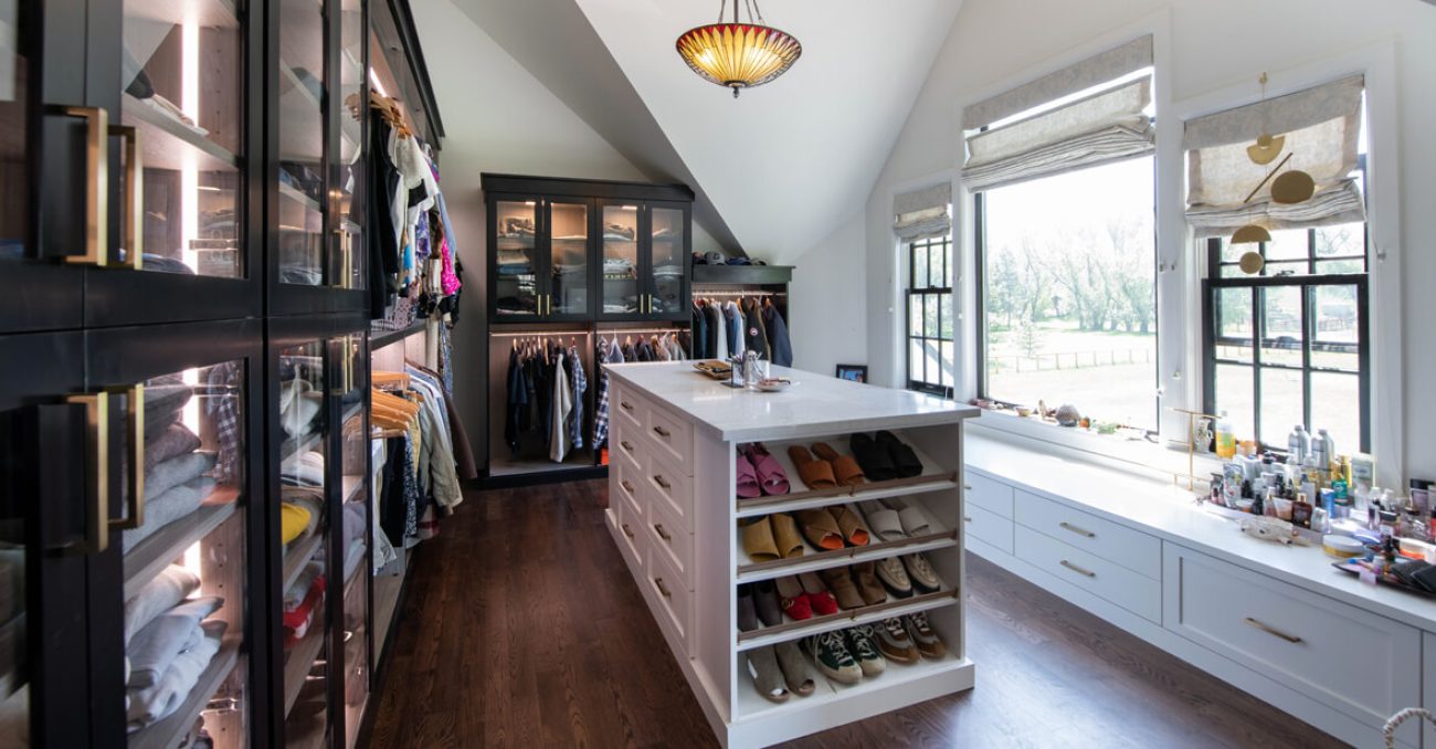 Stylish walk-in closet with black-framed glass cabinetry, island with shoe shelving