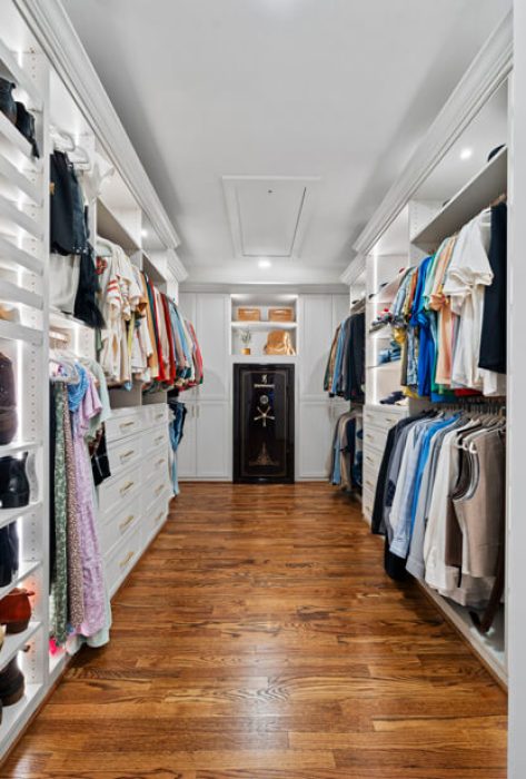 Classic closet with white cabinetry, black accent drawers, wood floors, and built-in wall safe