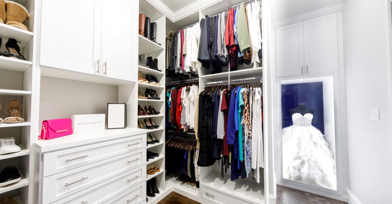 Custom walk-in with shaker cabinetry, full-extension drawers, and crown molding. Includes angled shoe shelves, double-hang sections, and a lit display niche for special garments.