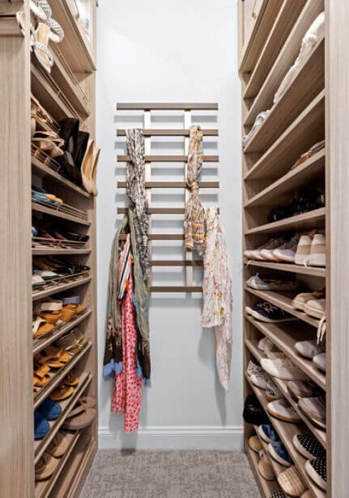 Shoe shelving display with adjustable rows and a wall-mounted rack for scarves and belts.