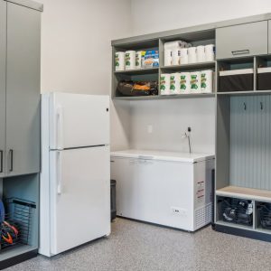 Gray mudroom-style garage design with full-height cabinets, wire baskets, overhead cubbies, and bench seating