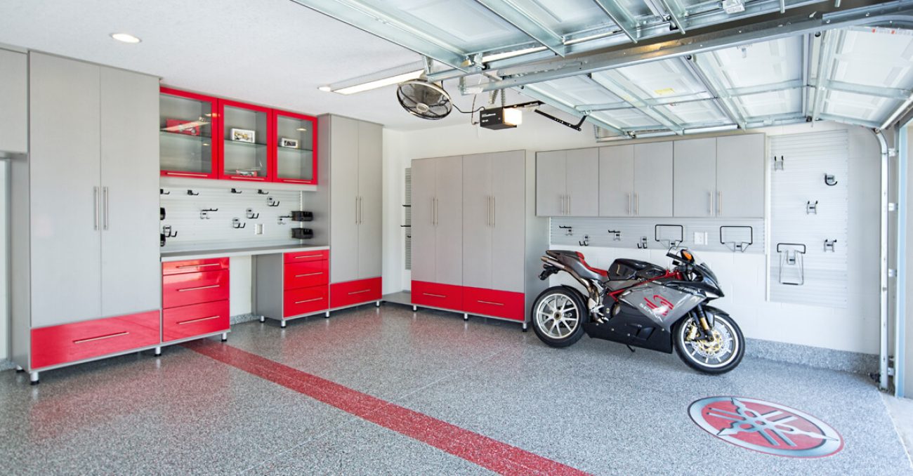 Garage with gray cabinets and glossy red drawers, slatwall organizer system, heavy-duty hooks, and epoxy flooring