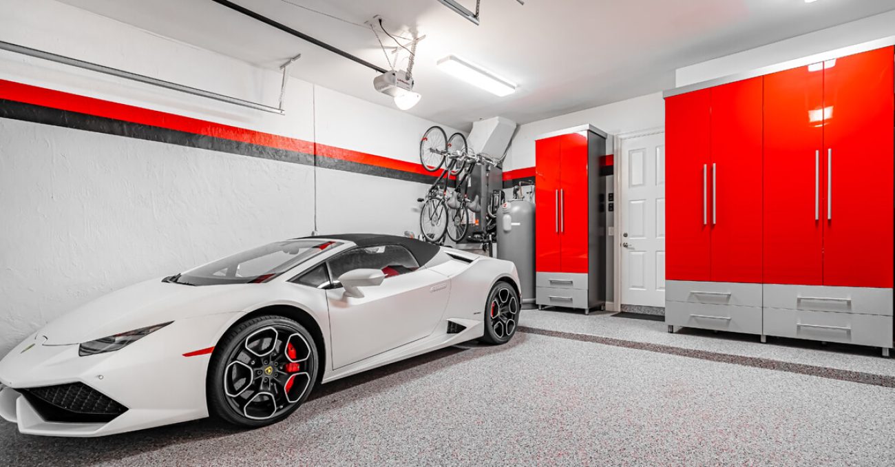 Luxury sports garage with high-gloss red cabinetry, gray base drawers, and vertical bike racks