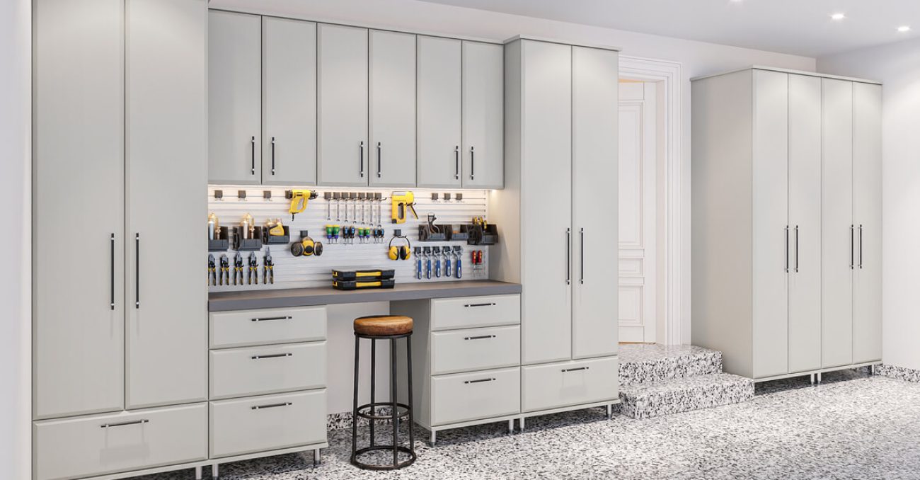Garage system with flat-panel cabinets in Dove Grey, featuring a built-in workbench, utility hooks, tool organizers, and a full-width metal Slatwall system.
