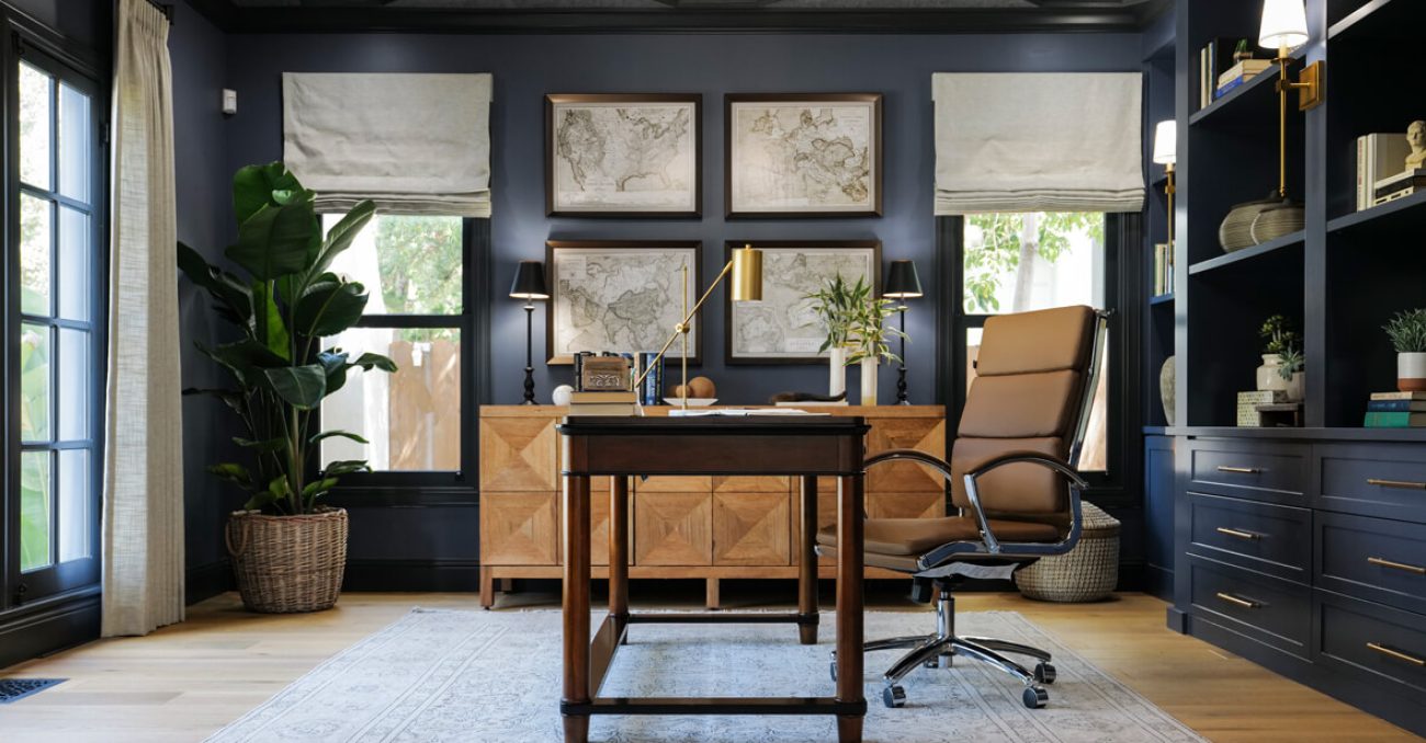Executive-style home office with fluted drawer fronts, integrated file storage, custom base cabinets, and library lighting