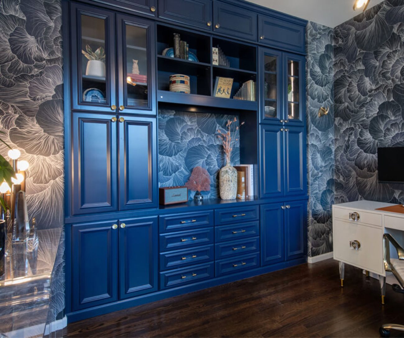 Bold home office built-in with deep blue shaker cabinetry, glass doors, crown molding, and display lighting