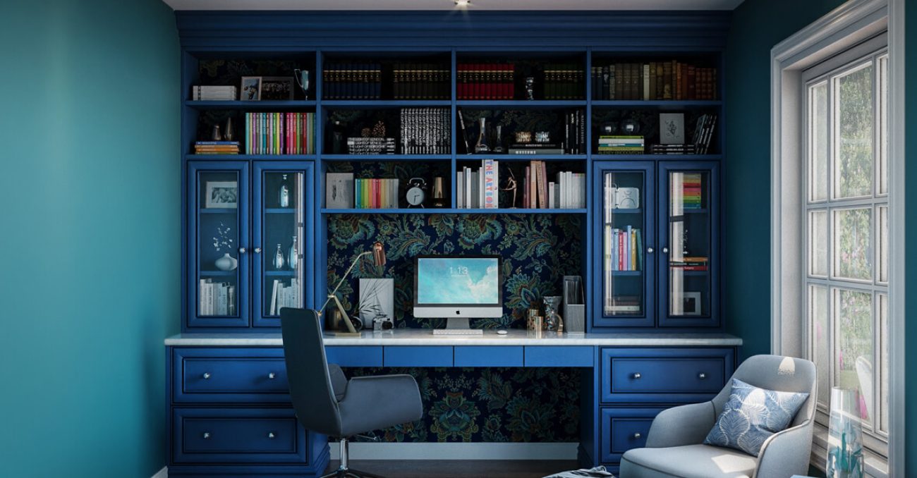 Custom home office with blue built-ins, glass-front cabinets, adjustable shelving, custom drawer inserts, and full wall backing in patterned wallpaper
