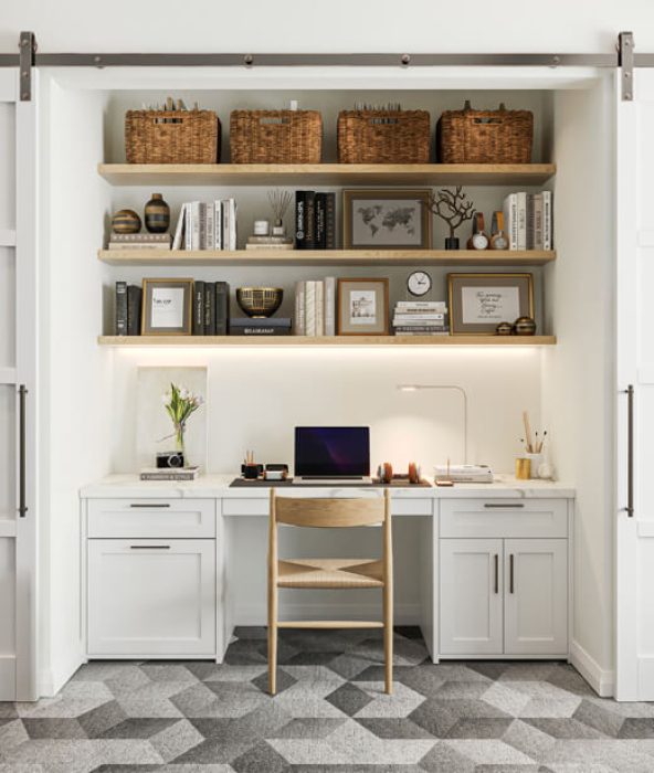 Compact, closet-style workstation with two-tier open shelving, wicker baskets, framed prints, and a flush-mount LED task light