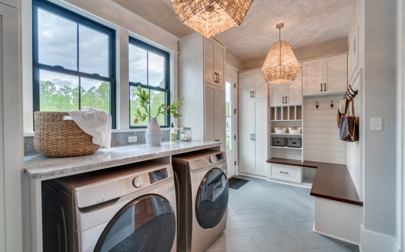 Custom laundry room and mudroom with folding station, built-in bench, coat hooks, and white shaker cabinetry.