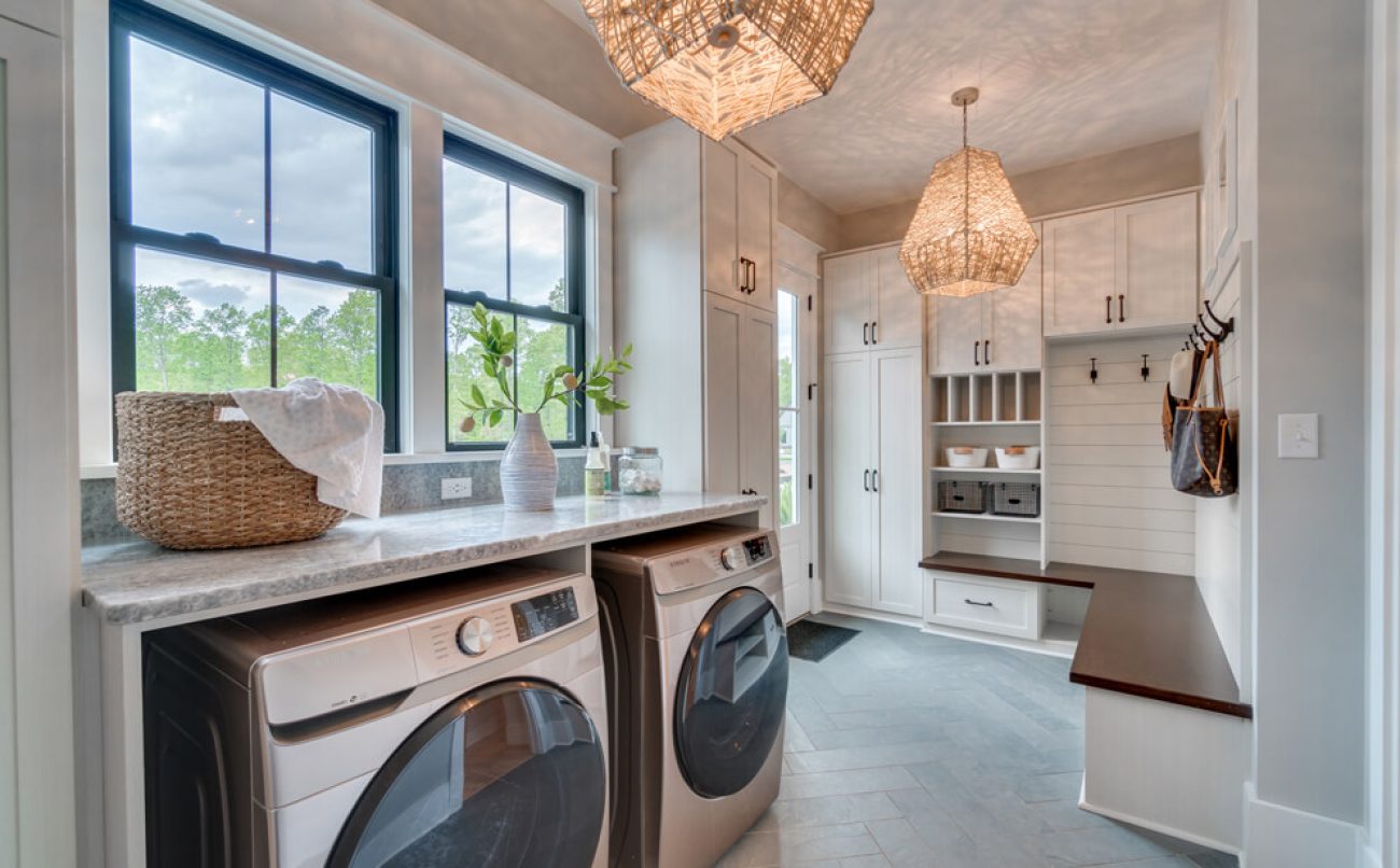 Spacious mudroom and laundry combo featuring a long bench with coat hooks, and multiple built-in storage compartments.