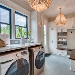 Spacious mudroom and laundry combo featuring a long bench with coat hooks, and multiple built-in storage compartments.