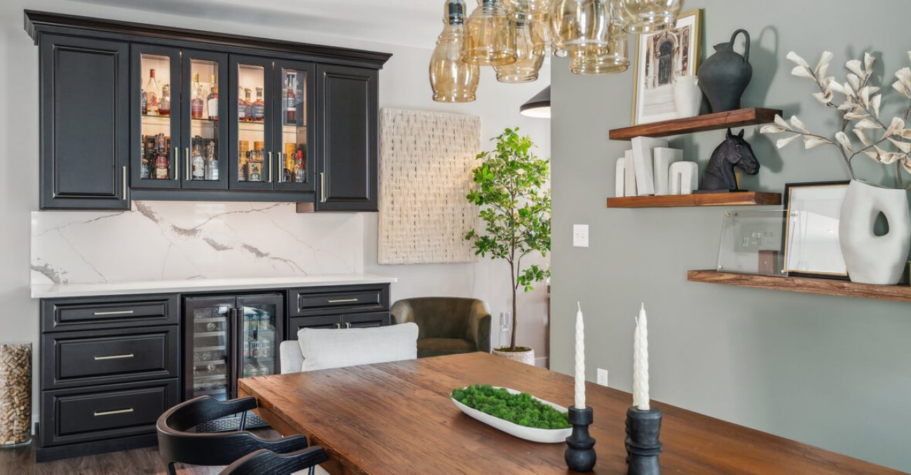 Sophisticated bar design in a dining space with glass-front black cabinets, white marble backsplash, dual beverage coolers, and decorative shelving.