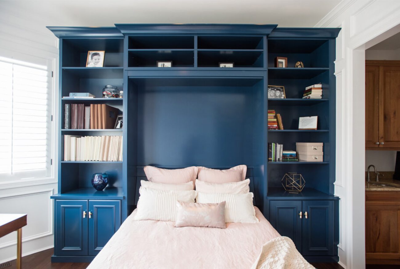 Custom wall bed cabinetry in navy blue with built-in bookshelves