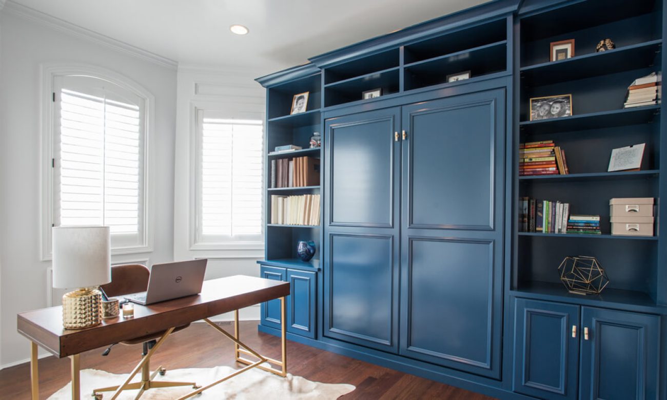 Custom wall bed cabinetry in navy blue with built-in bookshelves and concealed bed