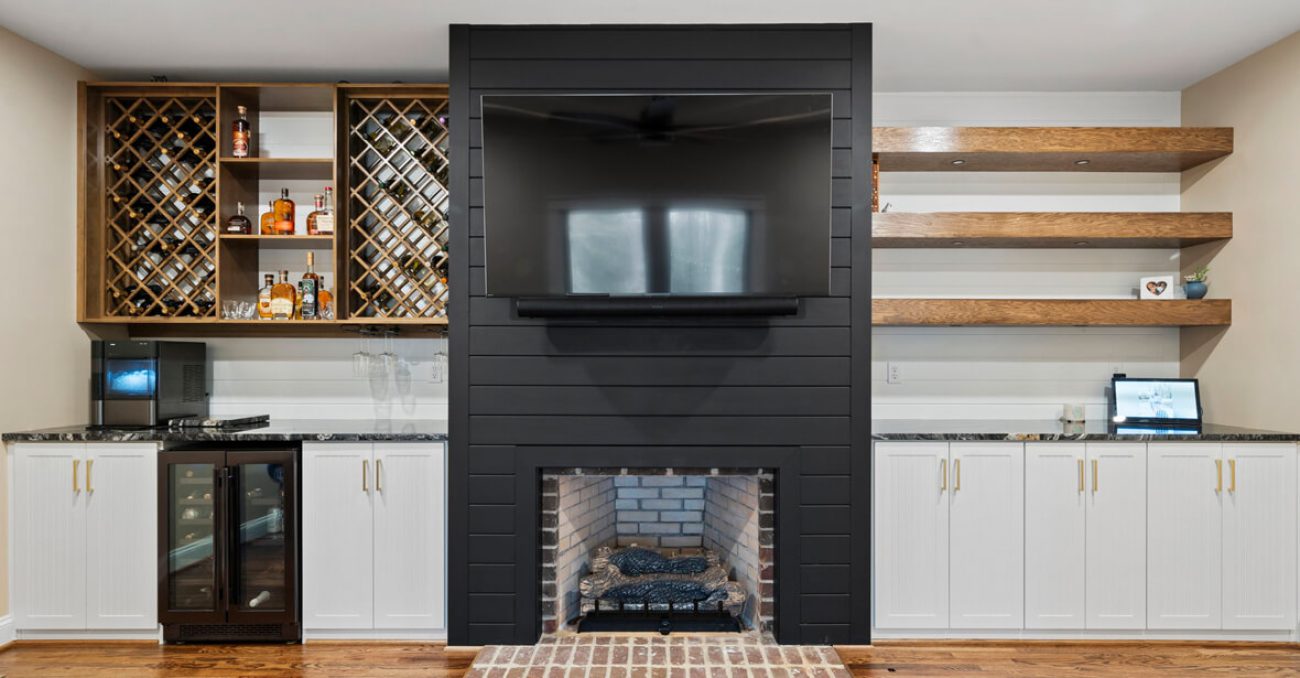 Custom wall unit with wine storage, glass cabinetry, and floating wood shelves flanking a fireplace and mounted TV
